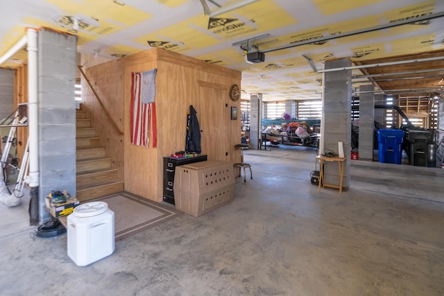 basement featuring stairway, wooden walls, and a garage