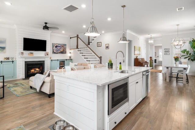 kitchen with visible vents, crown molding, open floor plan, appliances with stainless steel finishes, and a sink