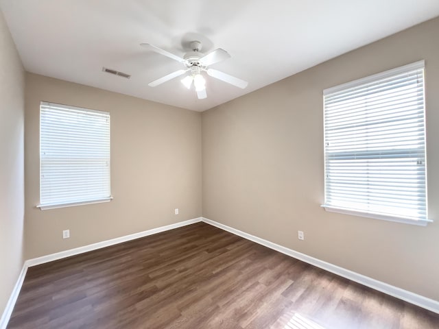 empty room with dark wood-style floors, baseboards, and a ceiling fan