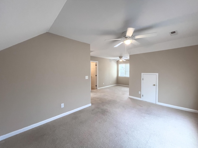 empty room featuring a ceiling fan, light carpet, baseboards, and vaulted ceiling