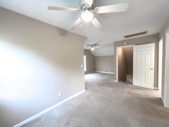 carpeted empty room featuring a ceiling fan, lofted ceiling, and baseboards