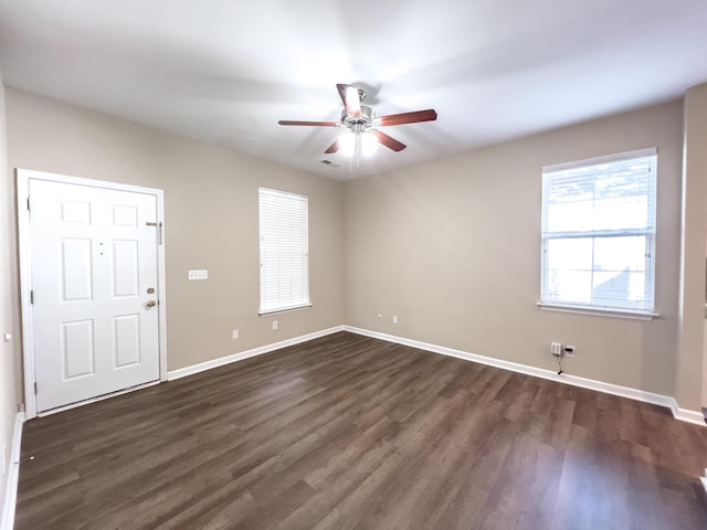 spare room with a ceiling fan, dark wood-type flooring, and baseboards