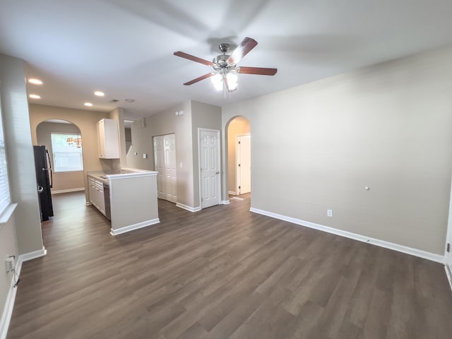 unfurnished living room with arched walkways, ceiling fan, baseboards, dark wood finished floors, and recessed lighting