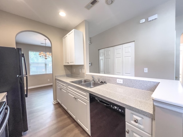 kitchen with black appliances, a sink, arched walkways, wood finished floors, and light countertops