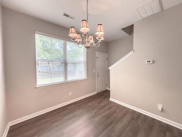 unfurnished dining area featuring dark wood-style flooring, a chandelier, and baseboards