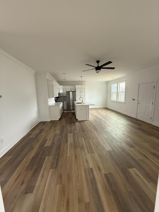 unfurnished living room with ornamental molding, a ceiling fan, and dark wood-style floors