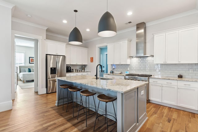 kitchen featuring sink, stainless steel appliances, white cabinets, and wall chimney exhaust hood