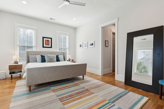 bedroom featuring light wood-type flooring, ceiling fan, and multiple windows