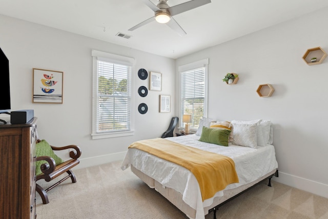 bedroom with light carpet, multiple windows, and ceiling fan