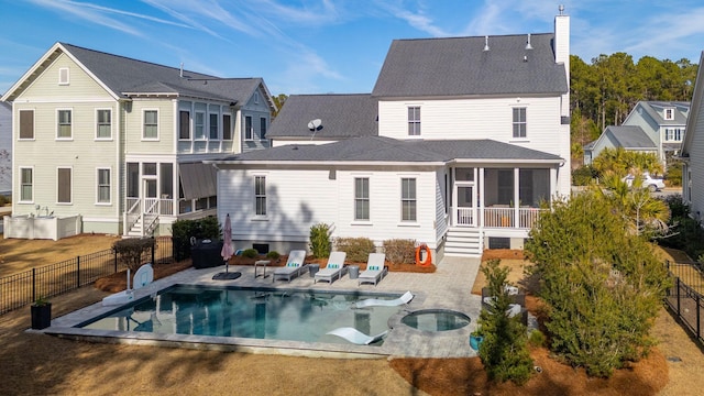 rear view of house featuring a fenced in pool, a sunroom, and a patio