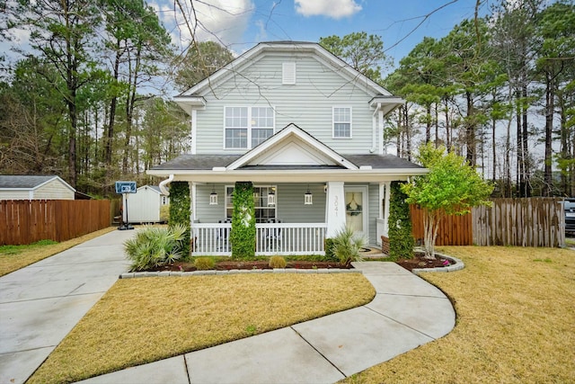 view of front facade with a front yard, covered porch, and fence