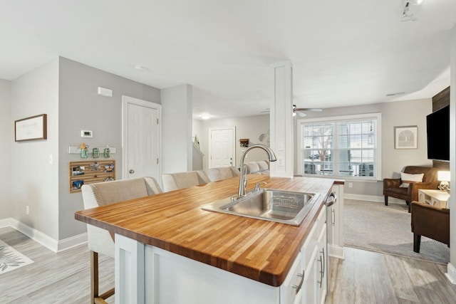 kitchen with open floor plan, white cabinetry, a sink, ceiling fan, and an island with sink