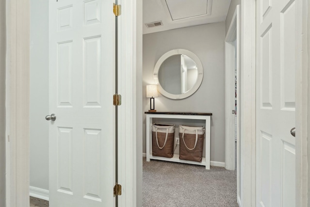 hall featuring baseboards, visible vents, and light colored carpet