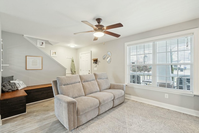 living room featuring a ceiling fan, light wood-style flooring, and baseboards