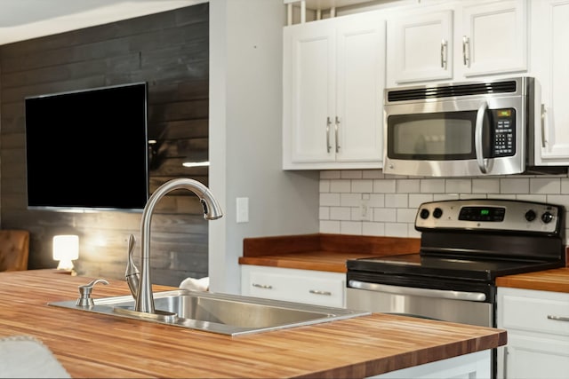 kitchen featuring tasteful backsplash, butcher block countertops, white cabinetry, and stainless steel appliances