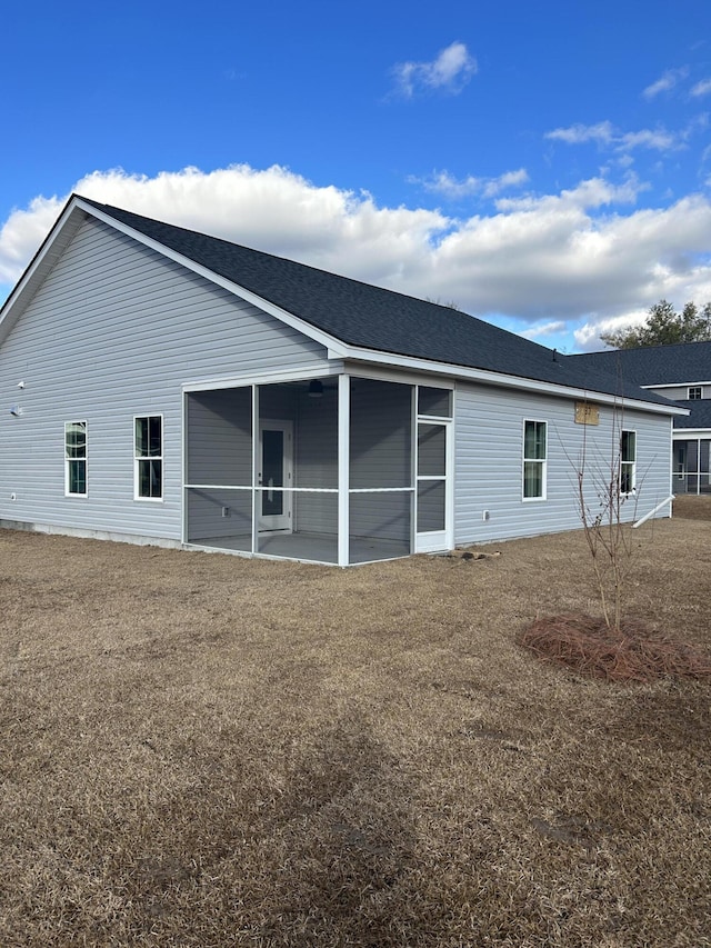 rear view of house featuring a sunroom and roof with shingles