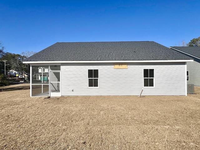 back of property with a shingled roof, a sunroom, and central air condition unit