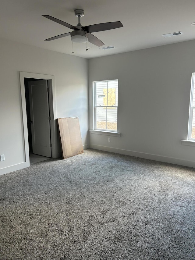 carpeted empty room with visible vents, a ceiling fan, and baseboards