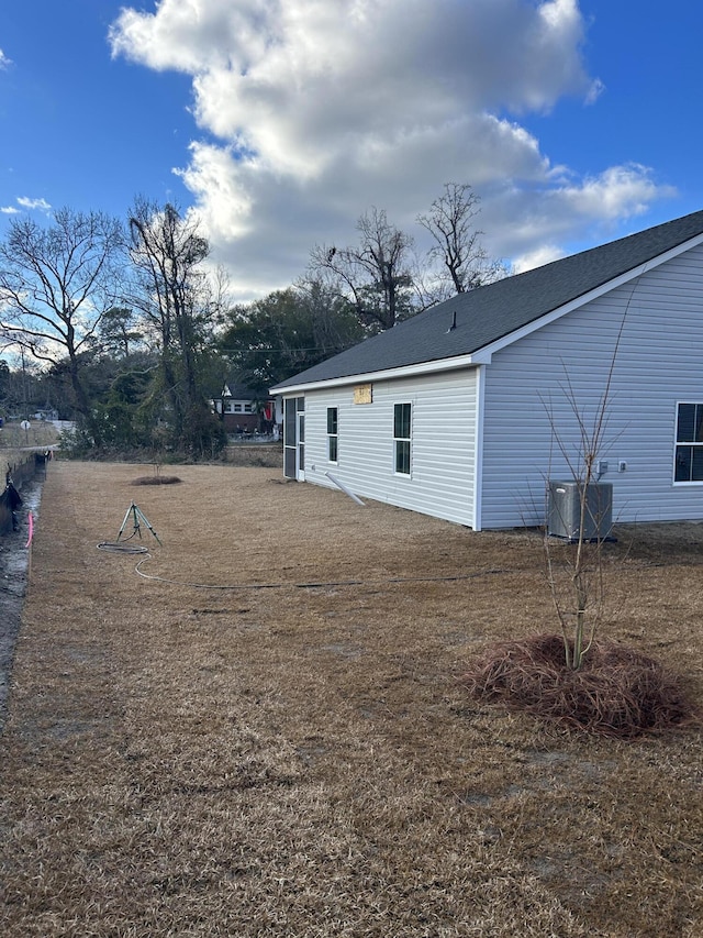 rear view of house featuring a shingled roof and central AC