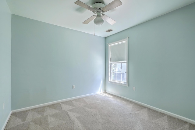 empty room featuring light colored carpet, baseboards, a ceiling fan, and visible vents