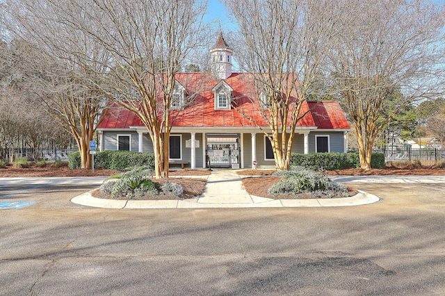 cape cod-style house featuring a porch and fence