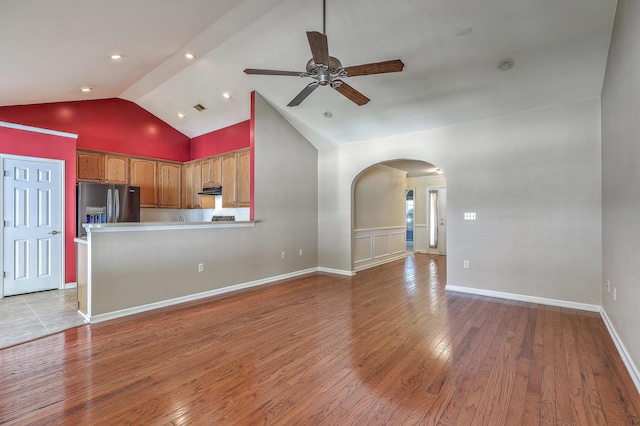 unfurnished living room with light wood-style floors, high vaulted ceiling, ceiling fan, arched walkways, and visible vents