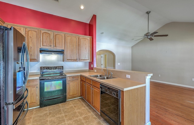 kitchen with a peninsula, black appliances, under cabinet range hood, lofted ceiling, and a sink