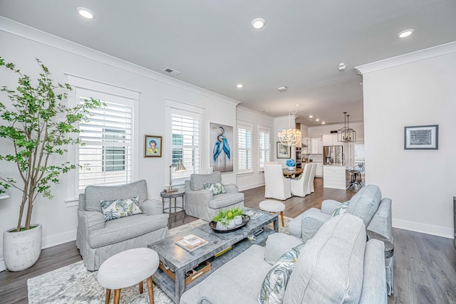 living room with crown molding, dark wood-type flooring, and a notable chandelier