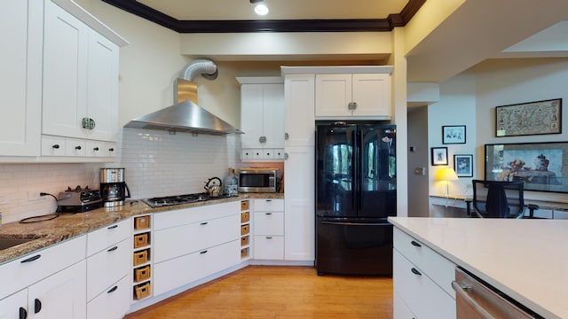 268 Little Oak Island Dr, Folly Beach, SC 29439 - kitchen featuring backsplash, stainless steel appliances, white cabinetry, light wood-type flooring, and wall chimney range hood