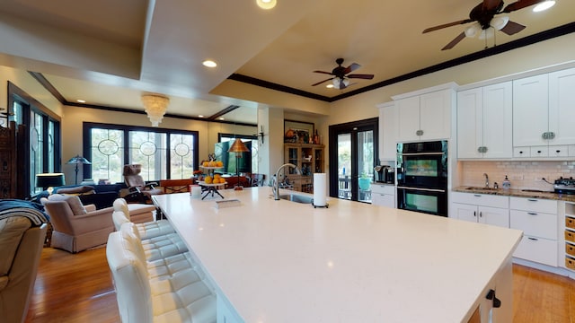 268 Little Oak Island Dr, Folly Beach, SC 29439 - kitchen with light wood-type flooring, black double oven, white cabinetry, and an island with sink