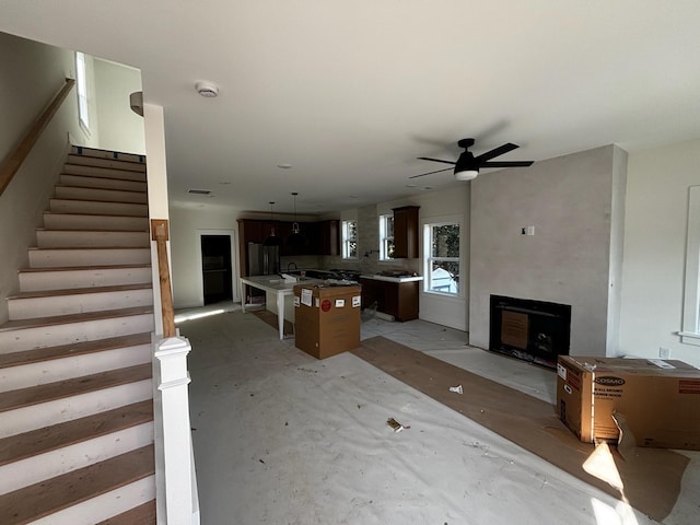 living room featuring ceiling fan and stairway