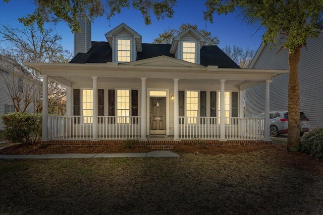 view of front facade with covered porch and a chimney