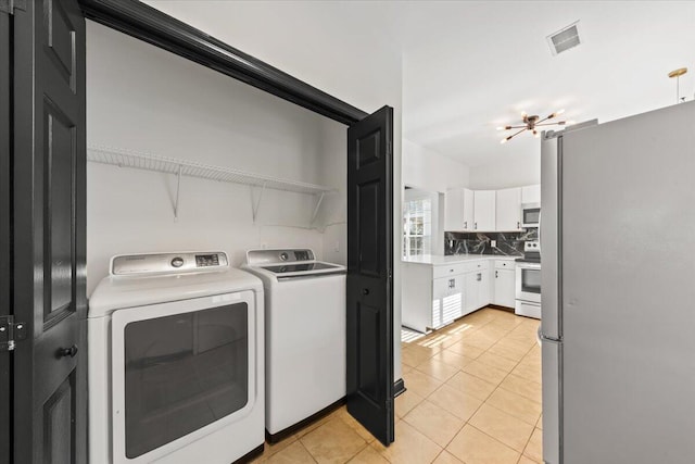 washroom with light tile patterned floors, visible vents, separate washer and dryer, and laundry area