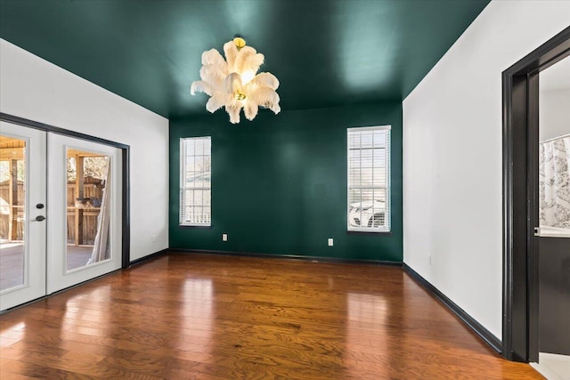 empty room featuring plenty of natural light, wood finished floors, baseboards, and french doors