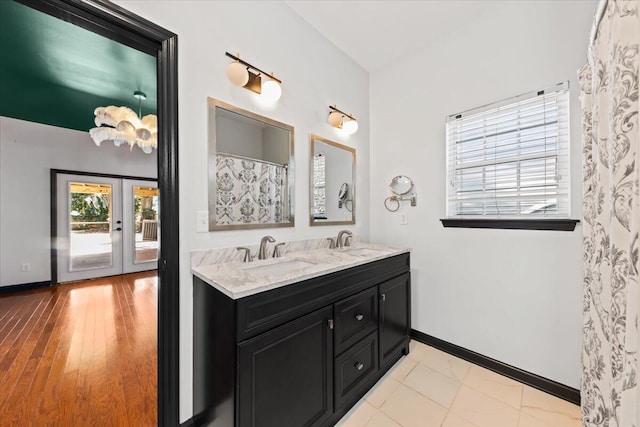 bathroom featuring double vanity, french doors, baseboards, and a sink