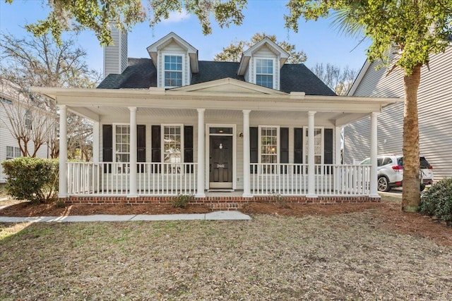 view of front of home with covered porch, a chimney, and a shingled roof