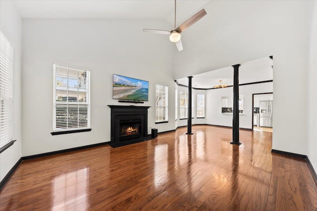 unfurnished living room featuring a fireplace with flush hearth, a healthy amount of sunlight, a ceiling fan, and wood finished floors