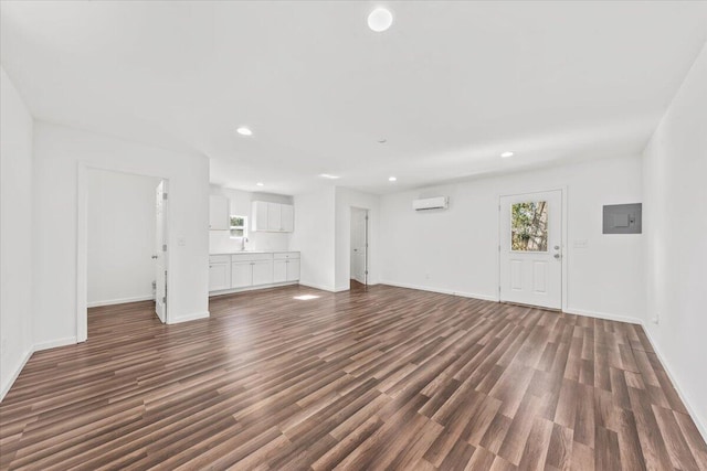 unfurnished living room featuring recessed lighting, electric panel, an AC wall unit, and dark wood-style floors