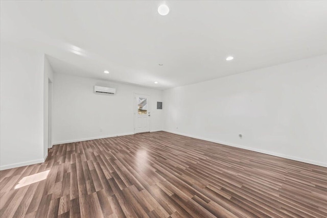 unfurnished room featuring recessed lighting, wood finished floors, baseboards, and a wall mounted AC