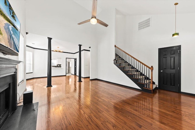 living room featuring visible vents, a ceiling fan, wood finished floors, stairway, and a fireplace