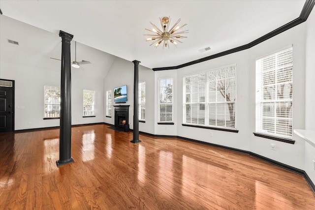 unfurnished living room with visible vents, a warm lit fireplace, and wood finished floors