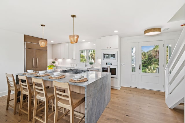 313 E Arctic Ave, Folly Beach, SC 29439 - kitchen featuring appliances with stainless steel finishes, a center island, light wood-style floors, white cabinets, and recessed lighting