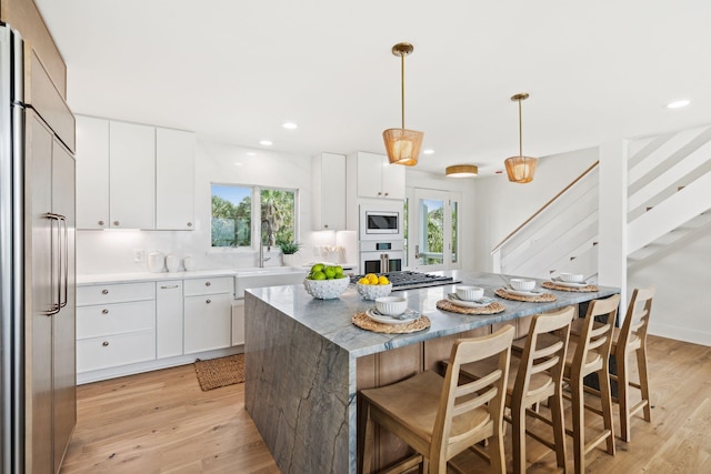 313 E Arctic Ave, Folly Beach, SC 29439 - kitchen with built in appliances, a sink, a kitchen island, light wood-style floors, and white cabinets