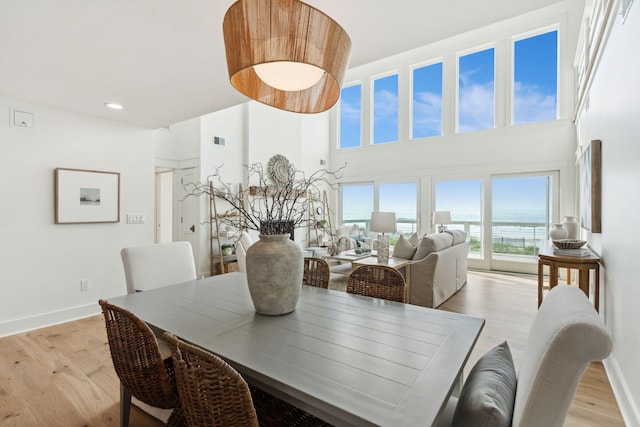 313 E Arctic Ave, Folly Beach, SC 29439 - dining area featuring baseboards, light wood-type flooring, and a high ceiling