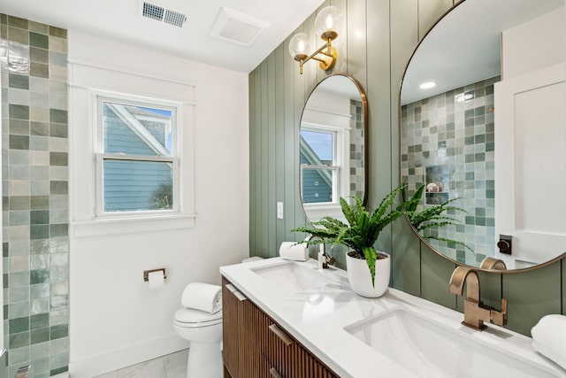 313 E Arctic Ave, Folly Beach, SC 29439 - bathroom featuring marble look tile flooring, double vanity, toilet, and plenty of natural light