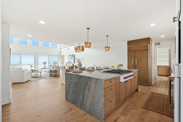 313 E Arctic Ave, Folly Beach, SC 29439 - kitchen featuring gas stovetop, paneled built in fridge, open floor plan, a center island, and light wood-style floors