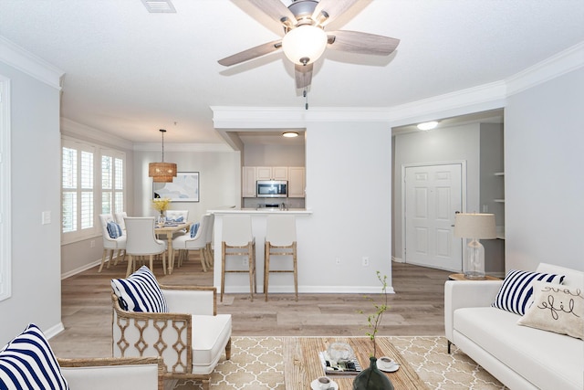 living room with ornamental molding, ceiling fan, and light hardwood / wood-style flooring