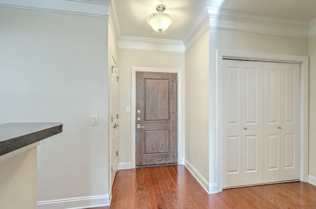 foyer entrance with crown molding, baseboards, and wood finished floors