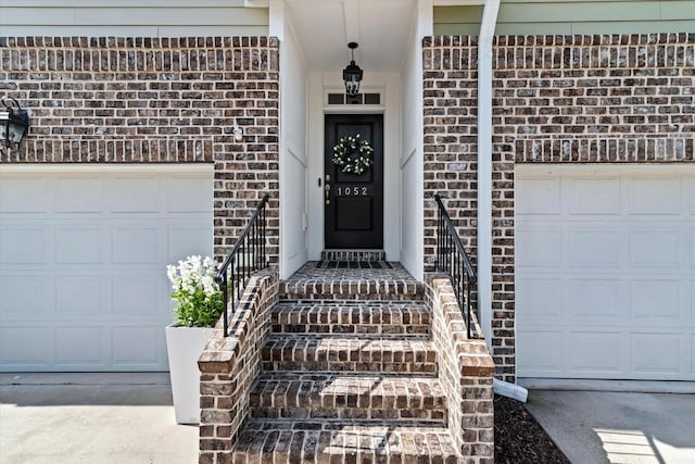 entrance to property with concrete driveway, brick siding, and an attached garage