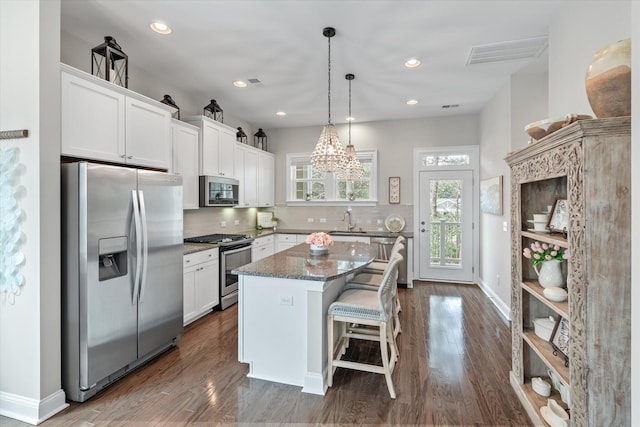 kitchen with appliances with stainless steel finishes, white cabinetry, a kitchen island, and a sink